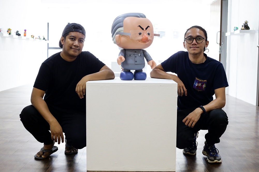 Titikmerah Collective’s co-founders Ajim Juxta and Aleff Ahmad pose for a photo with one of the figurines at the ‘Tun M Custom Show’ by HebatToys and TitikMerah at the TitikMerah Gallery in Kuala Lumpur September 25, 2019. 