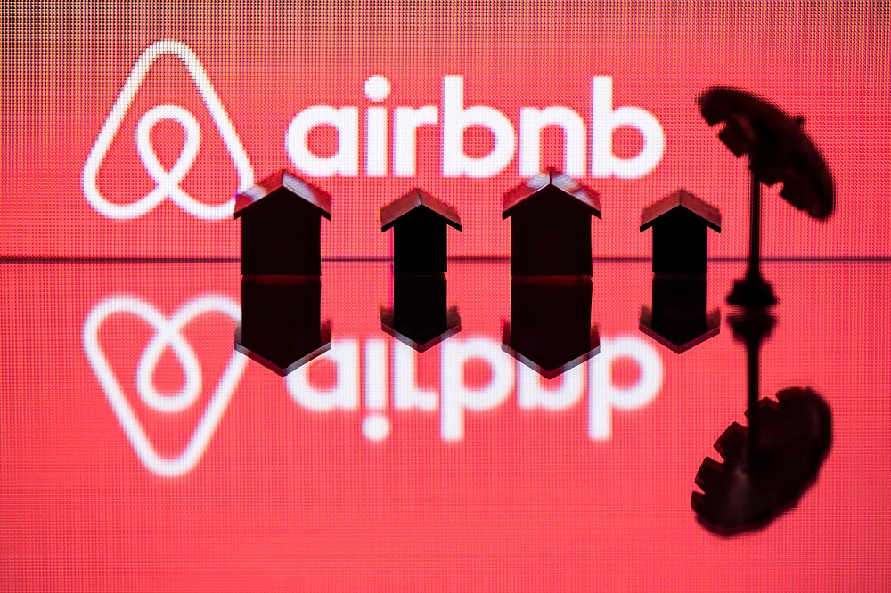 In this file illustration photo taken on August 29, 2018, shows a toy umbrella and houses next to the logo of rental website Airbnb. u00e2u20acu201d AFP pic            
