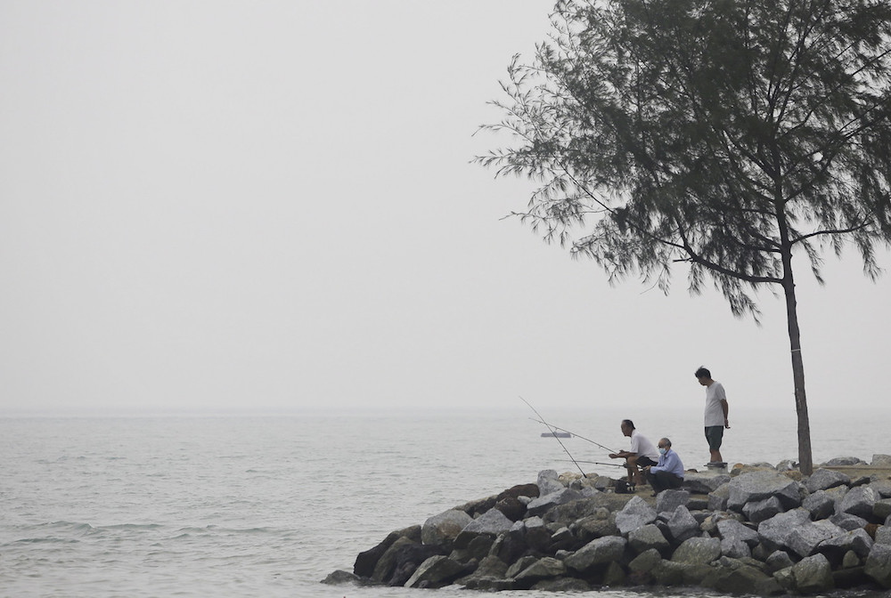 A man wears a mask as he fishes by the banks of Pantai Cahaya in Port Dickson September 21, 2019. u00e2u20acu201d Bernama pic