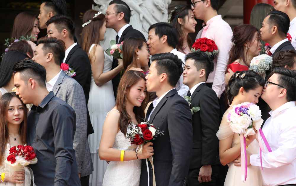 Newlywed couples kiss during a mass wedding at a Chinese temple in Kuala Lumpur September 9, 2019. u00e2u20acu2022 Reuters pic