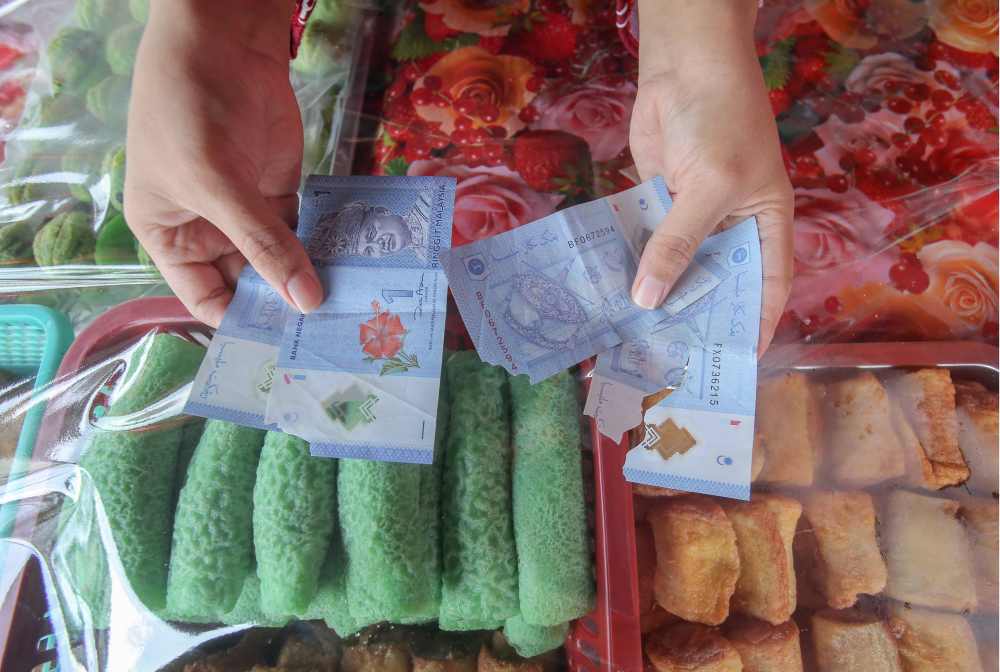 A trader shows the torn notes she received from customers. u00e2u20acu2022 Picture by Farhan Najib