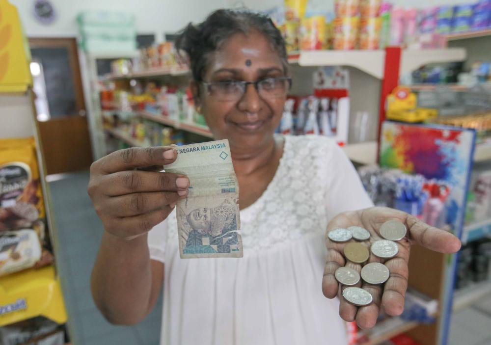 Grocery shop owner Magheswary Pitchay shows the damaged notes and also foreign coins she received from customers.