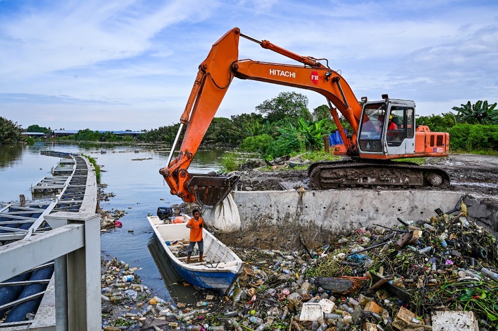 Workers clear mounds of floating plastic waste of the Klang River, in Klang, December 17, 2019. — AFP pic