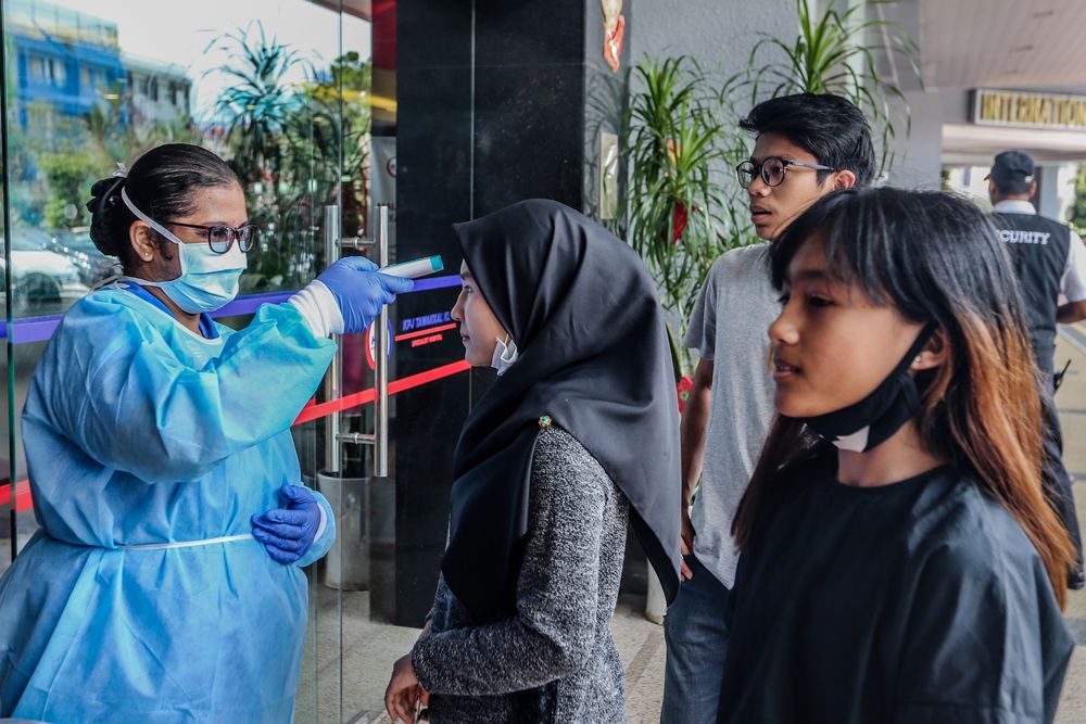 Medical personnel check the temperature of a visitor at the entrance of KPJ Tawakkal hospital in Kuala Lumpur. — Picture by Firdaus Latif