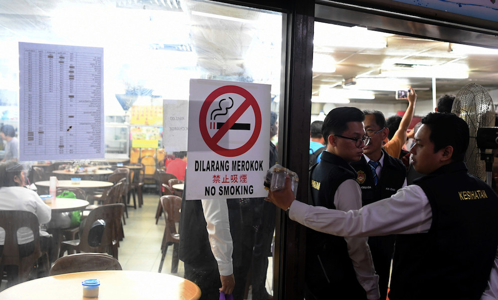 Health Department officers put up a no-smoking sign at a restaurant in George Town January 2, 2020. — Bernama pic