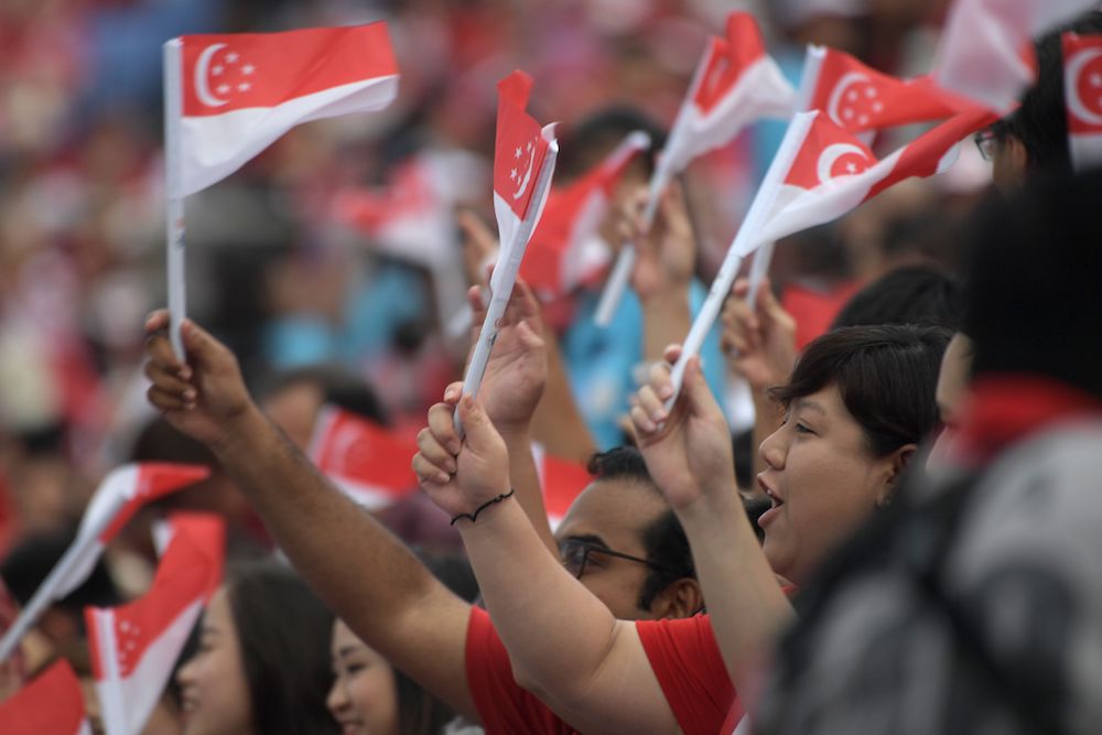 Spectators wave the Singapore national flag as they wait for the start of the 54th National Day Parade in Singapore August 9, 2019. u00e2u20acu201d AFP pic