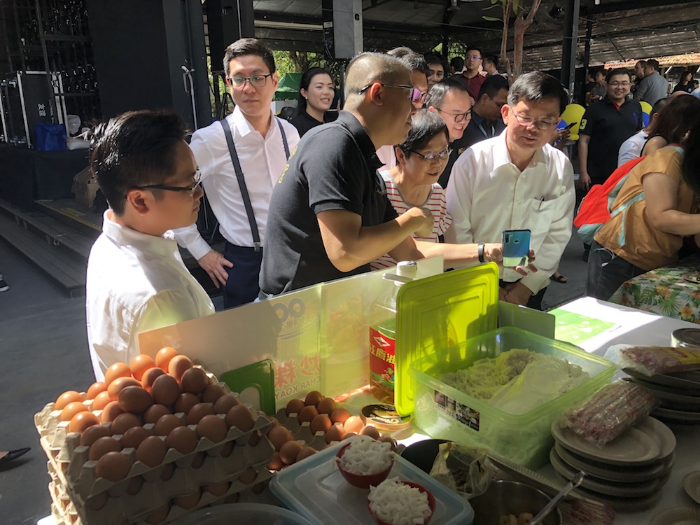 TNG Digital CEO Ignatius Ong (2nd left) shows Penang Chief Minister Chow Kon Yeow how to use the eWallet to make a payment at a char koay teow stall. u00e2u20acu201d Picture by Opalyn Mok