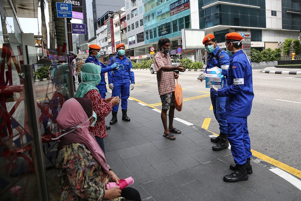 Malaysia Civil Defence Force personnel distributing protective face masks to the public in Kuala Lumpur March 21, 2020. u00e2u20acu201d Picture by Yusof Mat Isa