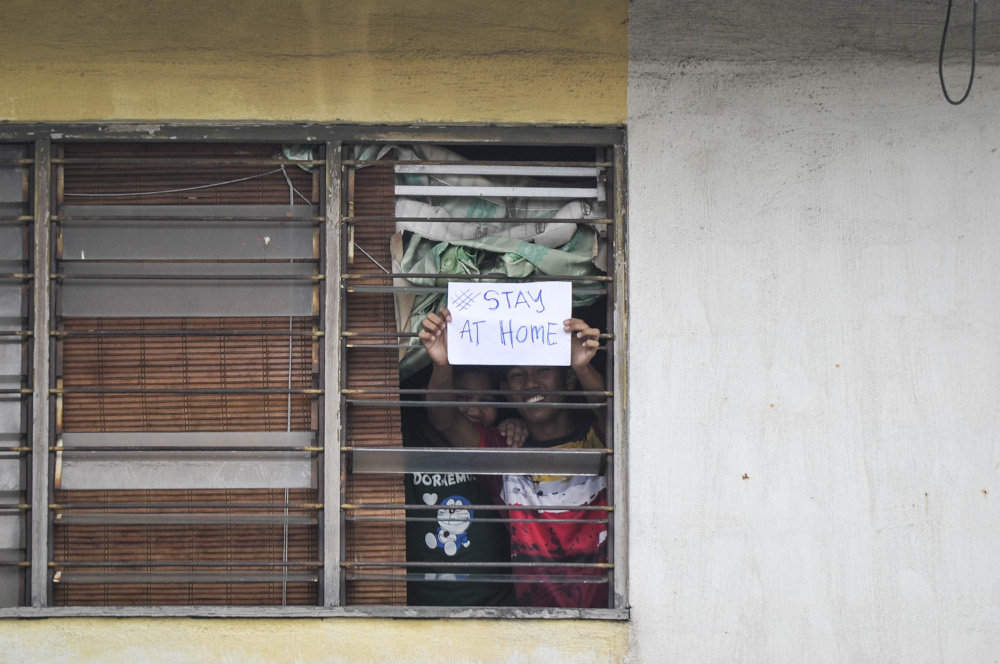 Petaling Jaya residents hold up a ‘#stayathome’ sign during the movement control order March 22, 2020. — Picture by Shafwan Zaidon