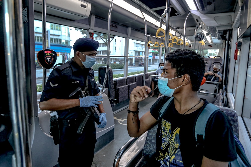 A Malaysian Armed Forces personnel conducts a routine check on bus passengers at a roadblock in Kuala Lumpur March 25, 2020. u00e2u20acu201d Picture by Firdaus Latif