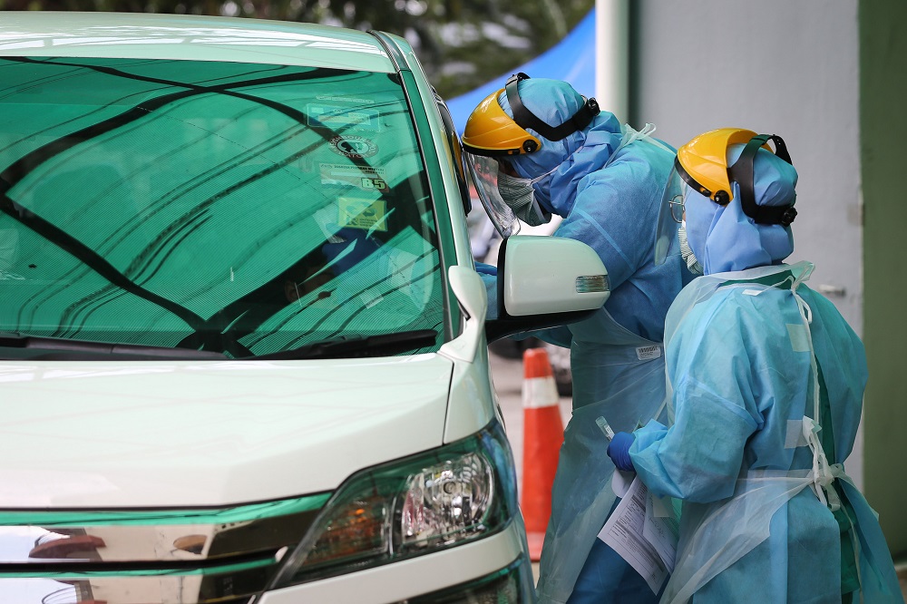 A health worker in protective suit swabs a driveru00e2u20acu2122s mouth at a drive-through testing site for Covid-19 at KPJ Damansara Specialist Hospital in Petaling Jaya March 28, 2020. u00e2u20acu201d Picture by Yusof Mat Isa