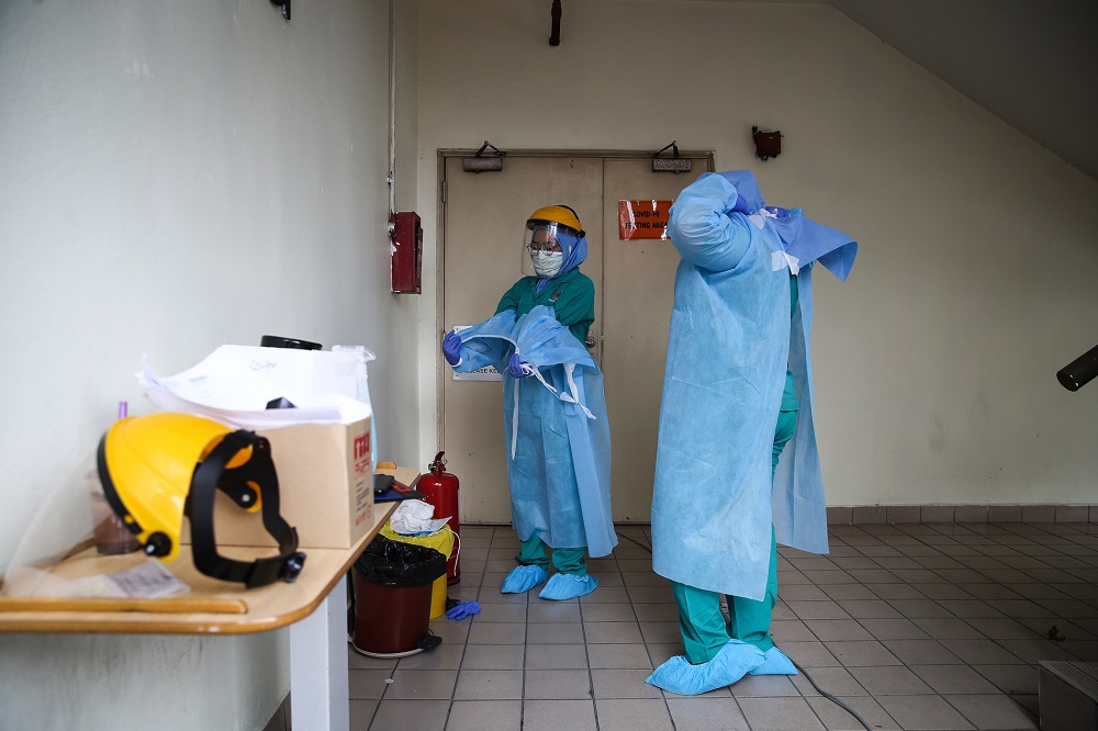 Health workers in protective suits are seen at a drive-through testing site for Covid-19 at KPJ Damansara Specialist Hospital in Petaling Jaya March 28, 2020. u00e2u20acu201d Picture by Yusof Mat Isa