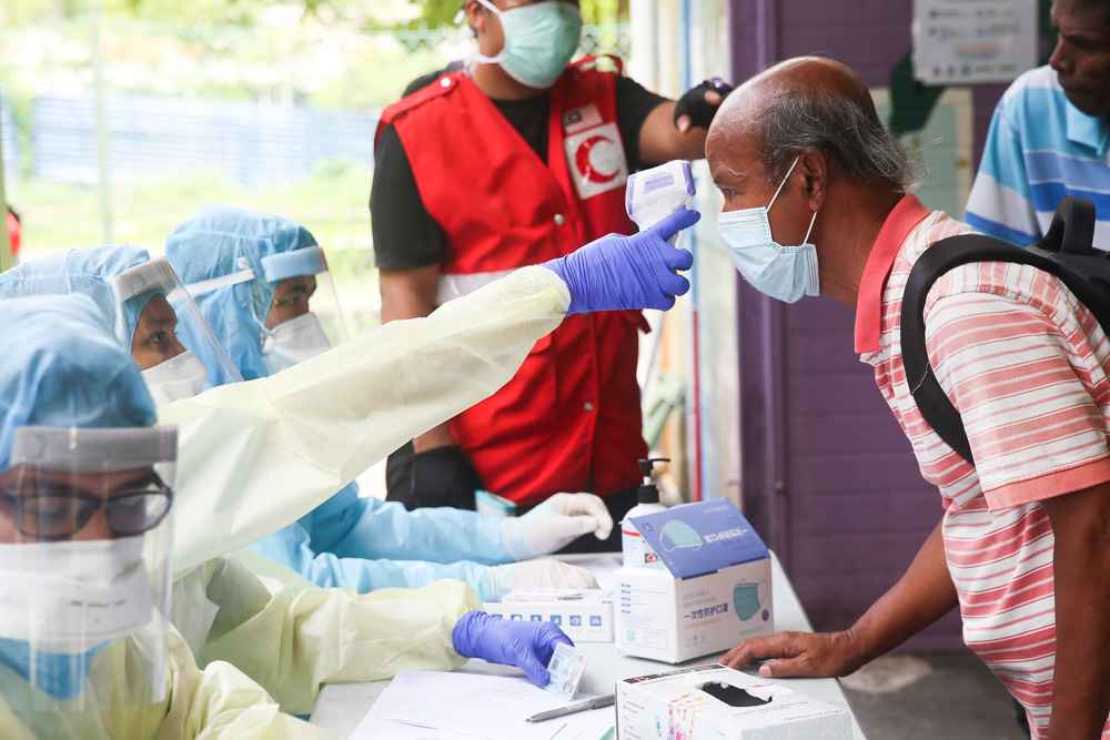 Health Ministry personnel screened individuals for fevers as part of Covid-19 precautions, before sending them to transit centres for the homeless during the MCO March 30, 2020. — Picture by Choo Choy May.