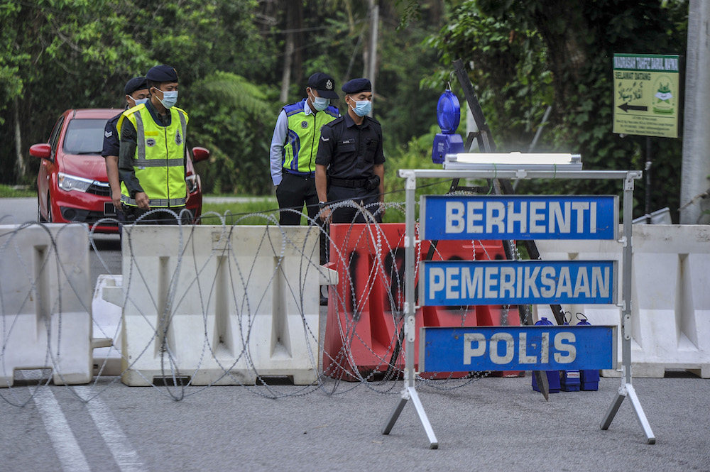 Police officers conducting checks at a roadblock during the enhanced movement control order (EMCO) in seven villages in Hulu Langat, March 30, 2020. — Picture by Shafwan Zaidon