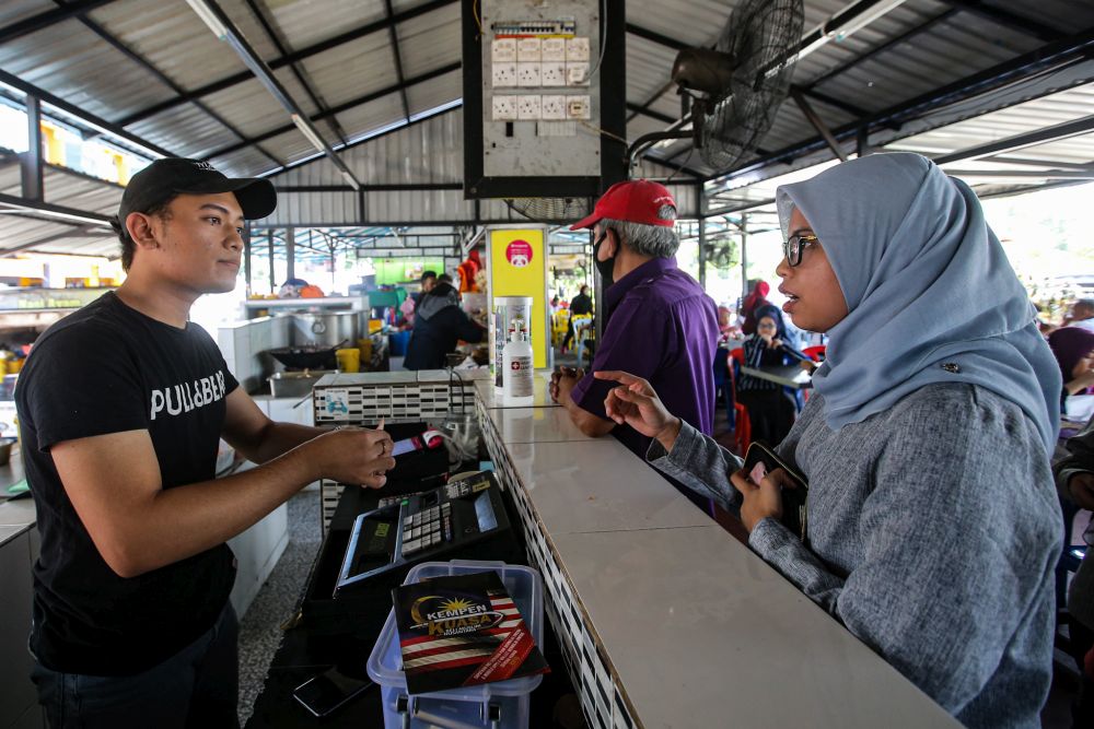 Amirul Asyrah Nazri speaks to a customer at his eatery Nasi Ayam Warisan in Kota Damansara March 17, 2020. u00e2u20acu201d Picture by Hari Anggara