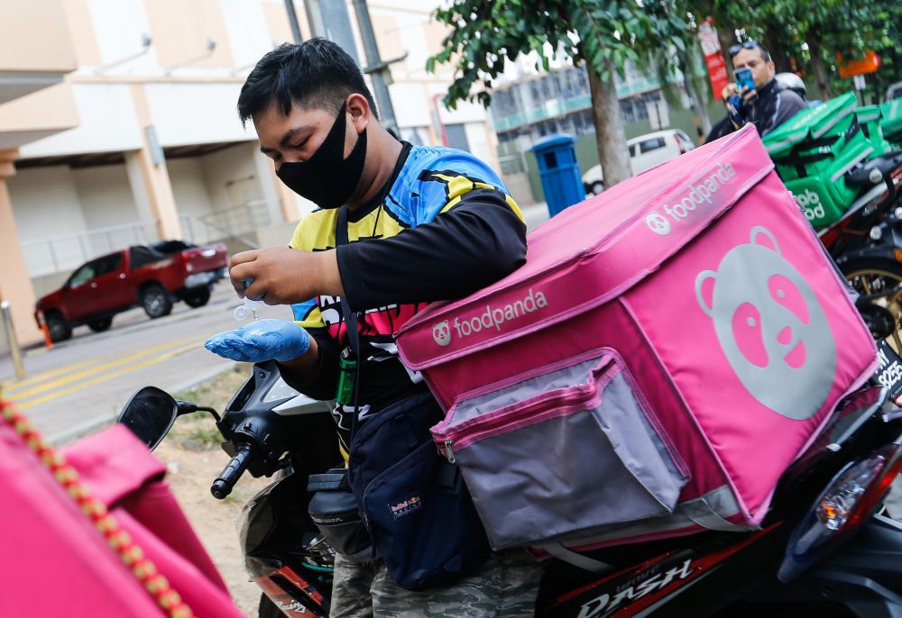 A Foodpanda rider is pictured sanitising his hands before making a delivery in Penang on day seven of the movement control order March 24, 2020. u00e2u20acu201d Picture by Sayuti Zainudin