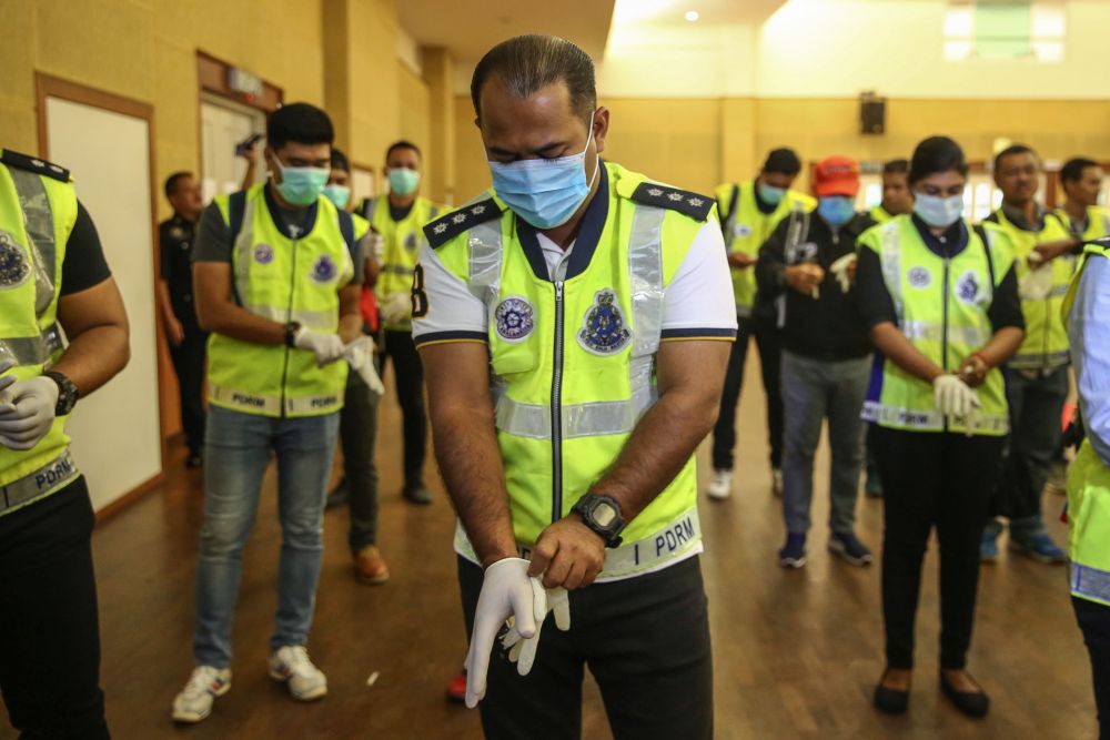 Police personnel put on their face masks and gloves during Ops Covid-19 in Shah Alam March 19, 2020. u00e2u20acu201d Picture by Yusof Mat Isa