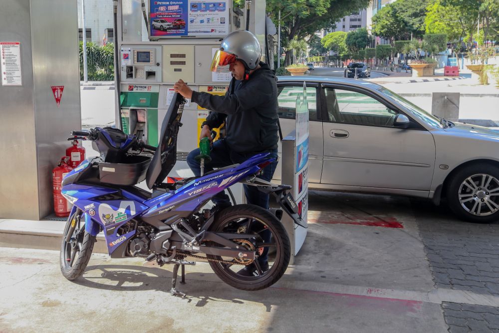 A man refuels his motorcycle at a petrol station in Kuala Lumpur as the movement control order kicks in on March 18, 2020. u00e2u20acu201d Picture by Firdaus Latif