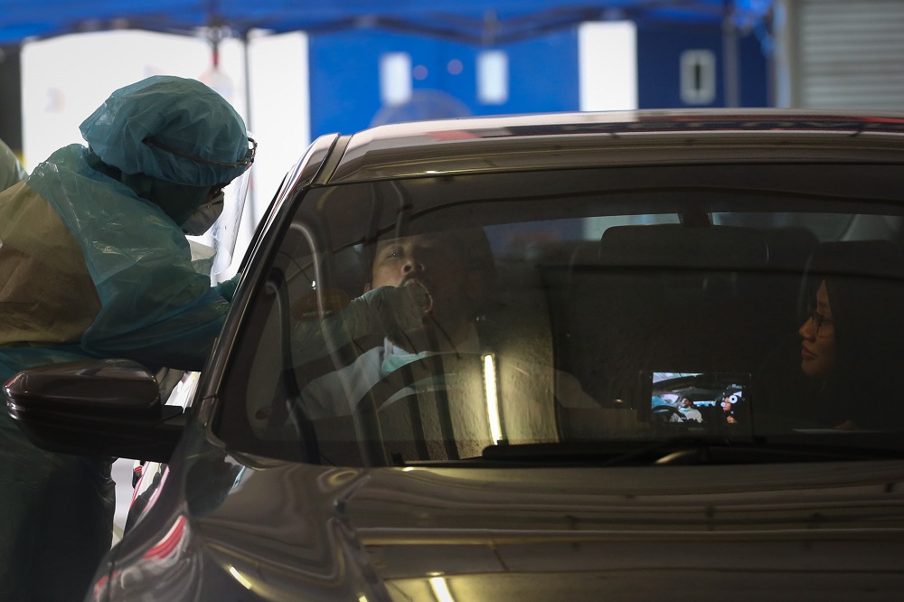 A health worker in protective suit collects swab samples from a motorist at a drive-through testing site for Covid-19 at MSU Medical Centre in Shah Alam April 10, 2020. —  Picture by Yusof Mat Isa