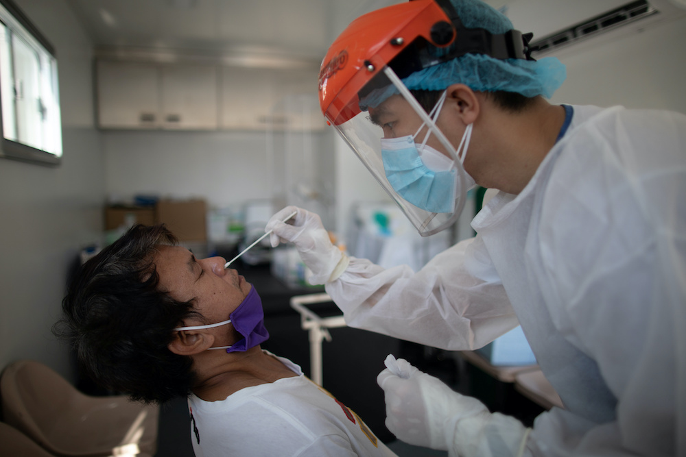 A nurse gets a swab from a man under observation for coronavirus disease in a booth set up in a hospital parking lot in Manila, Philippines, April 15, 2020. u00e2u20acu201d  Reuters picn n