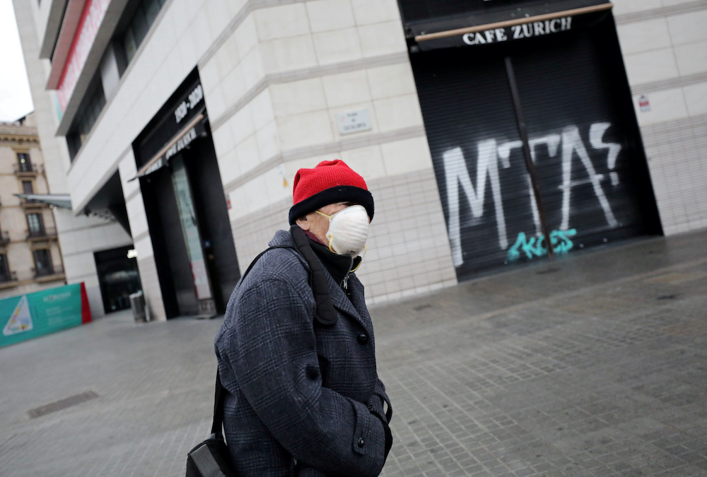 A man in a protective mask walks past a closed cafe near Catalonia Square during partial lockdown as part of a 15-day state of emergency to combat the coronavirus disease outbreak, in Barcelona, Spain March 16, 2020. u00e2u20acu201d Reuters pic