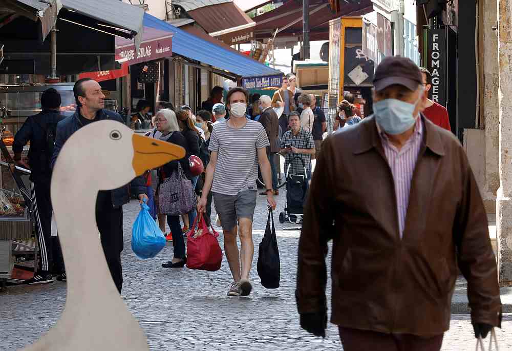 People wearing protective face masks shop in a street in Paris during a lockdown imposed to slow the rate of Covid-19 in France, April 24, 2020. u00e2u20acu201d Reuters pic