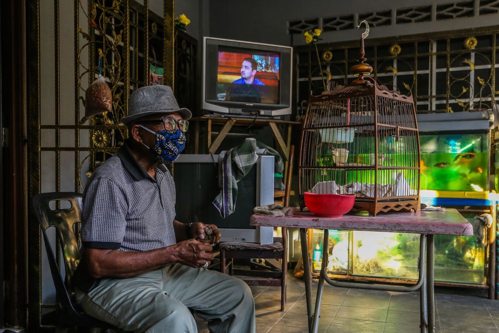 A man feeds his pet bird on his front porch during the movement control order in Gombak April 23, 2020. u00e2u20acu201d Picture by Firdaus Latif