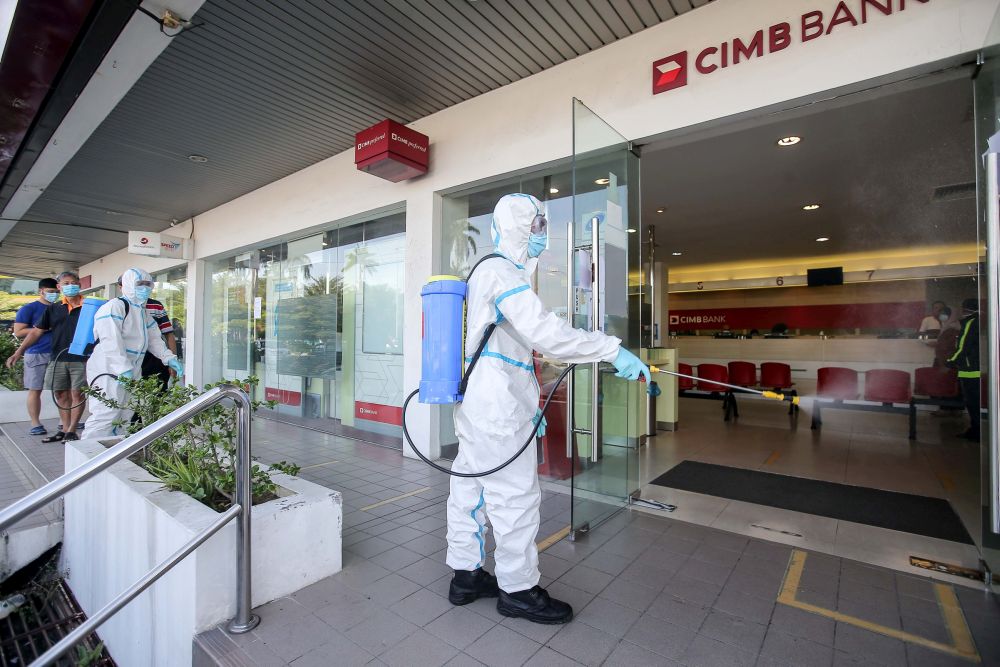 A city council worker sprays disinfectant at a CIMB Bank branch in Ipoh April 6, 2020. u00e2u20acu201d Picture by Farhan Najib