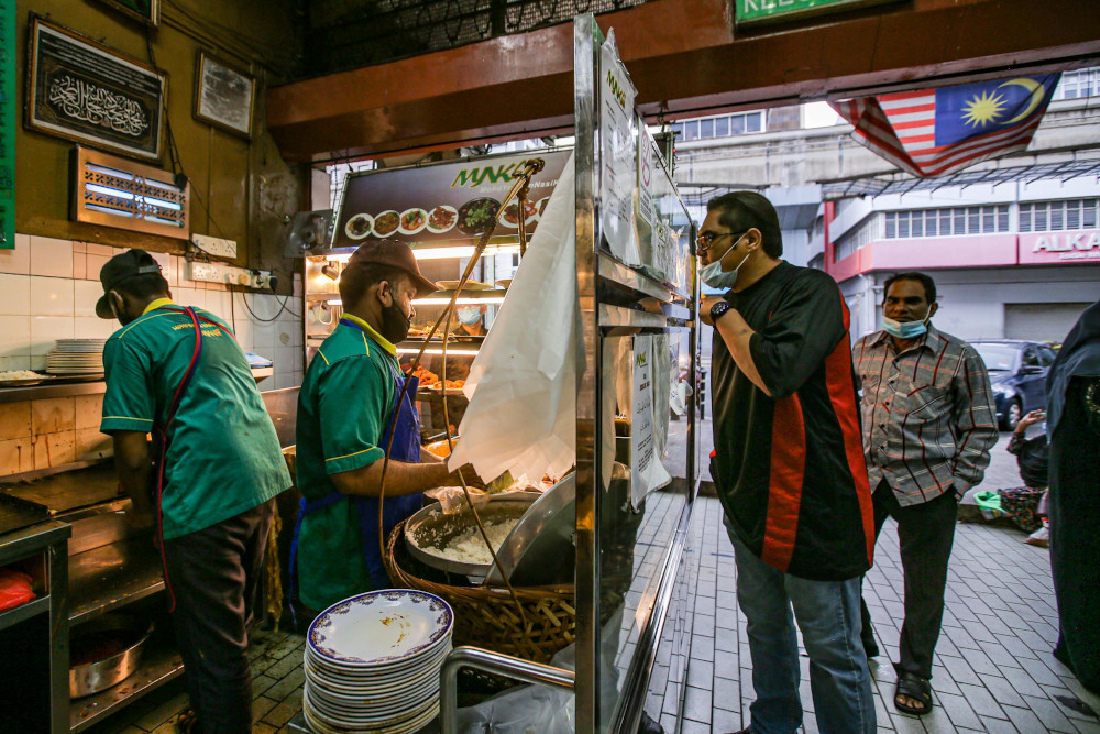 Customers queue up to buy food at Nasi Kandar Yaseem in Kuala Lumpur on the first day of the conditional movement control order May 4, 2020. — Picture by Hari Anggara 