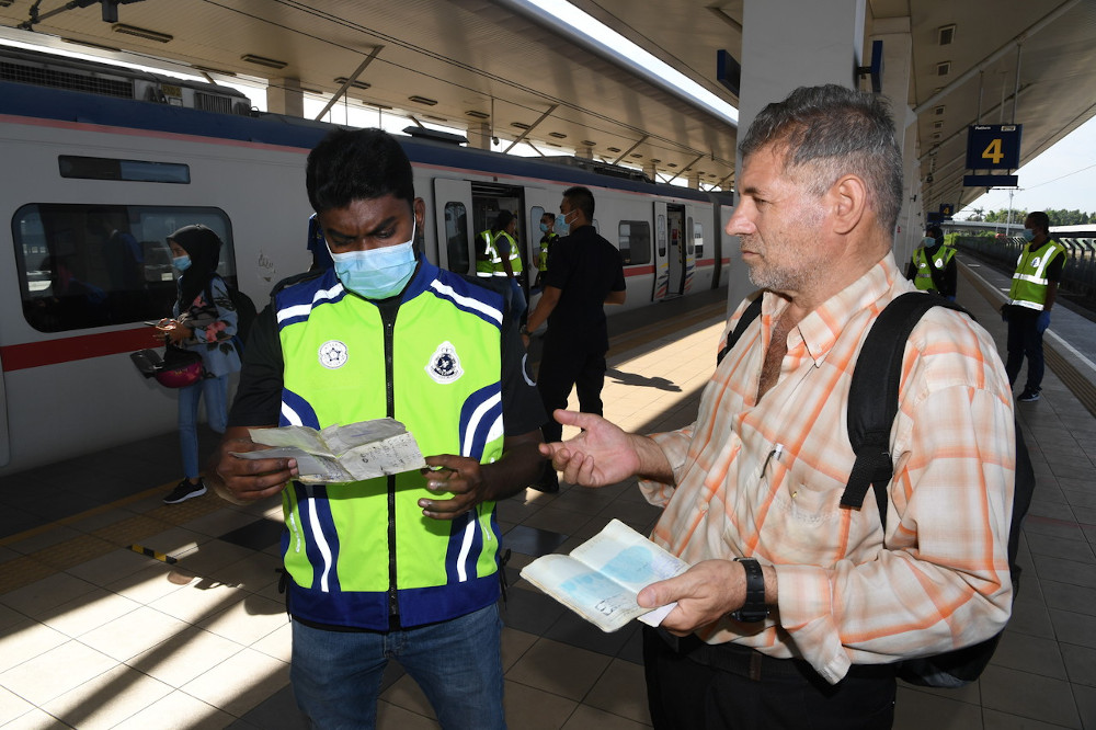 A man hands documents to a police officer during an inspection at the Butterworth KTMB station May 28, 2020. u00e2u20acu201d Bernama picn