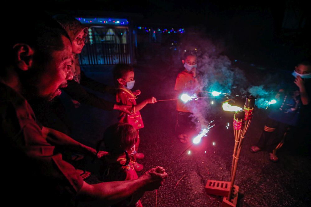 Children wearing face masks are pictured playing with sparklers in front of their homes in Kampung Changkat, Gombak on the eve of Hari Raya Aidilfitri May 23, 2020. u00e2u20acu201d Picture by Hari Anggara