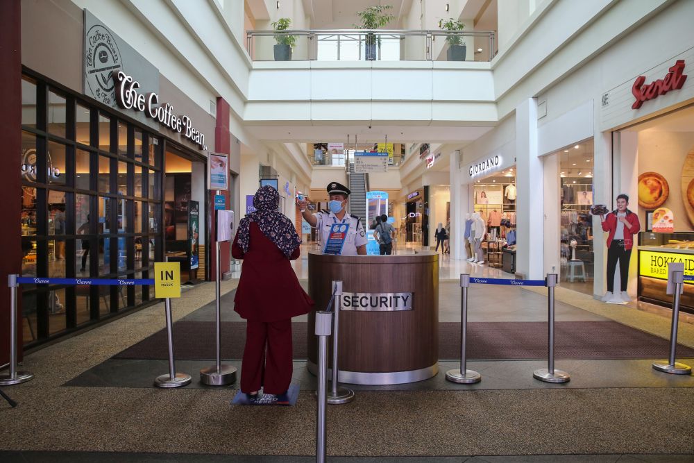 A security personnel checks a patron’s temperature at The Curve shopping mall entrance in Petaling Jaya May 28, 2020. — Picture by Yusof Mat Isa