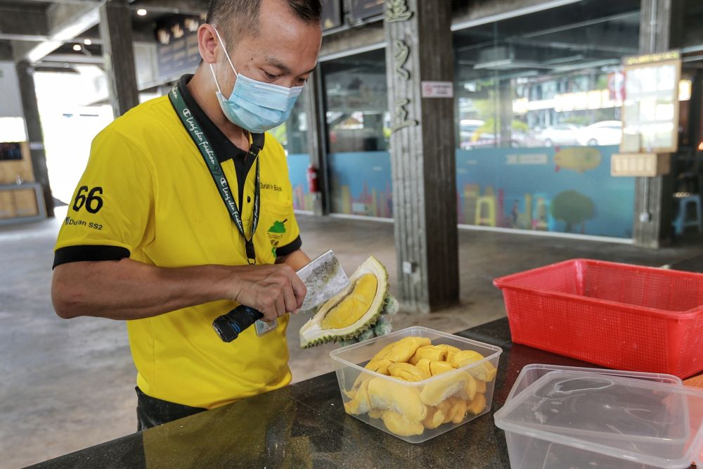 A worker fills a plastic container with durian in Petaling Jaya June 8, 2020. — Picture by Ahmad Zamzahuri