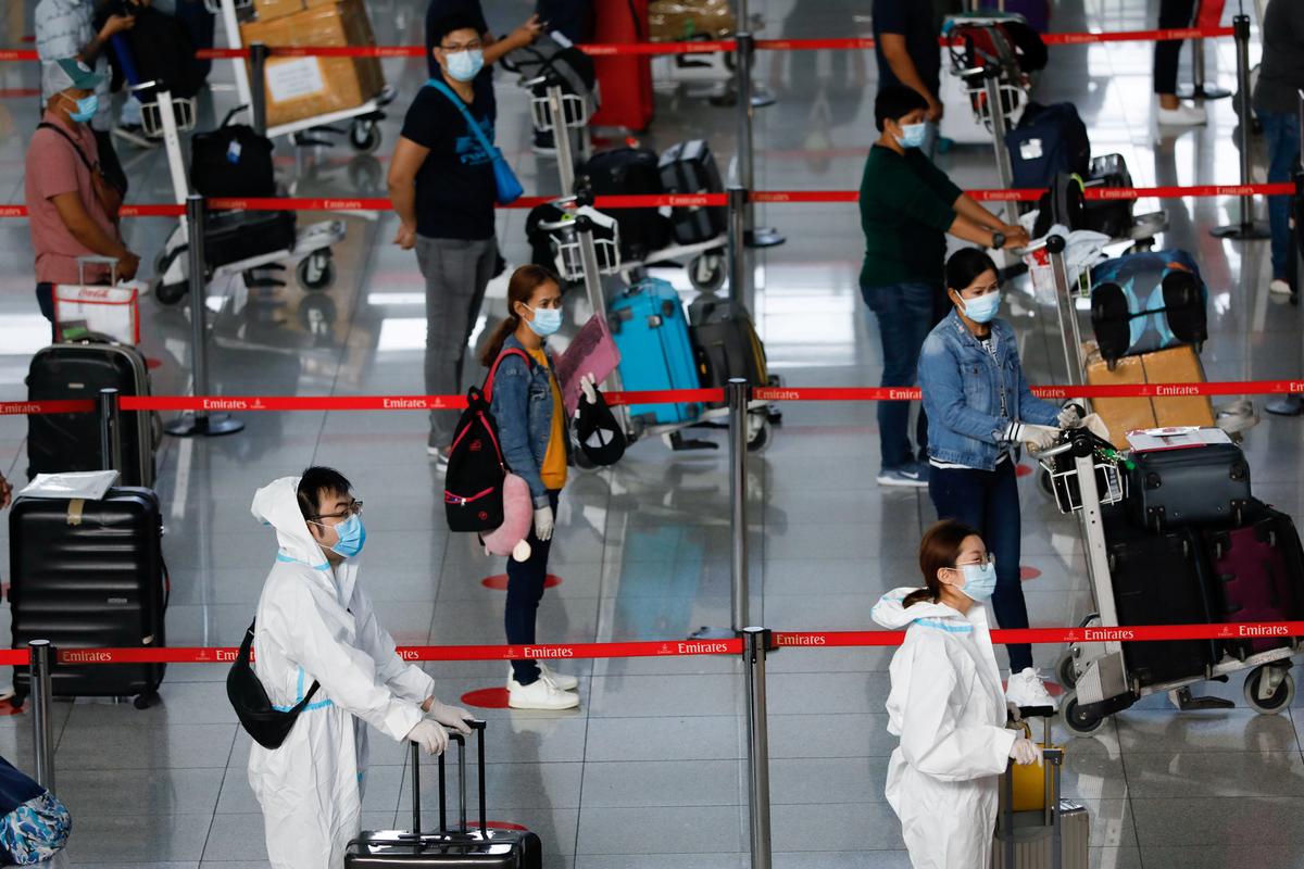 FILE PHOTO: Passengers wearing personal protective equipment for protection against the coronavirus disease (COVID-19) queue at the check-in counters of Emirates airline, in Ninoy Aquino International Airport in Pasay City, Metro Manila, Philippines, July