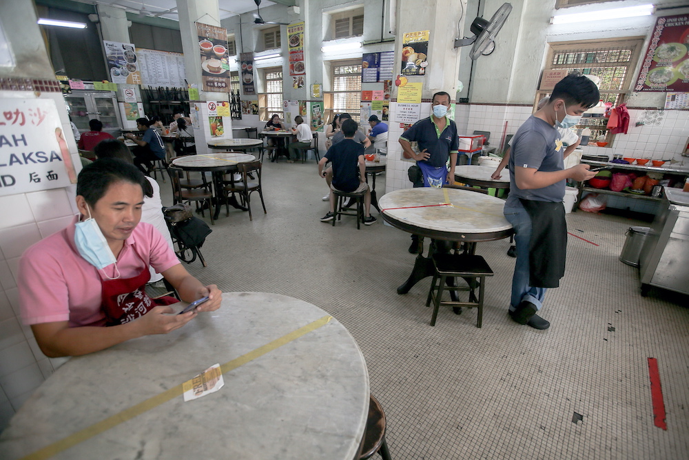 Stall owners in Restoran Ipoh Kong Heng take a breather. After months of lockdown due to the Covid-19 pandemic, Ipoh Town is gradually returning to its lively bustling atmosphere. — Picture by Farhan Najib