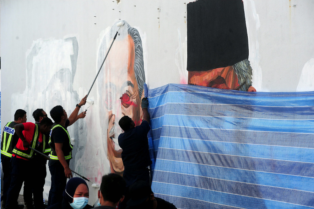 Shah Alam City Council (MBSA) workers paint over the defaced mural depicting Covid-19 heroes in Taman Cahaya Alam, Shah Alam July 20, 2020. — Bernama pic