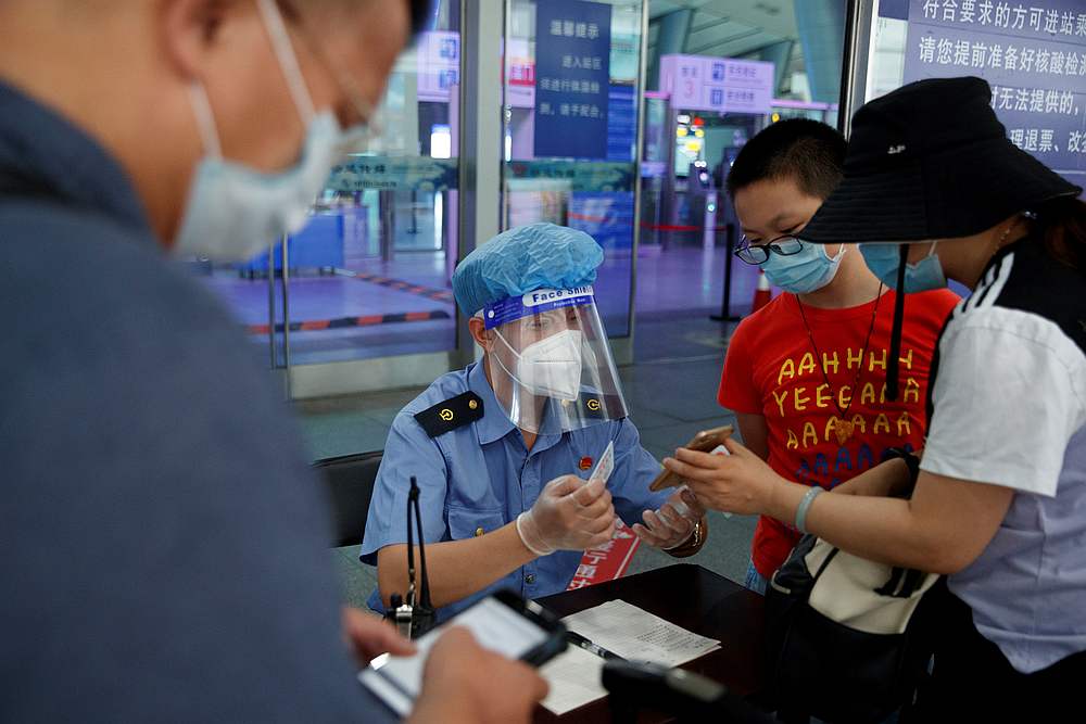 A station staff member wears protective gear as he checks the ID and health status of travellers before they enter the Beijing South Railway Station in Beijing, China July 3, 2020. u00e2u20acu201d Reuters pic