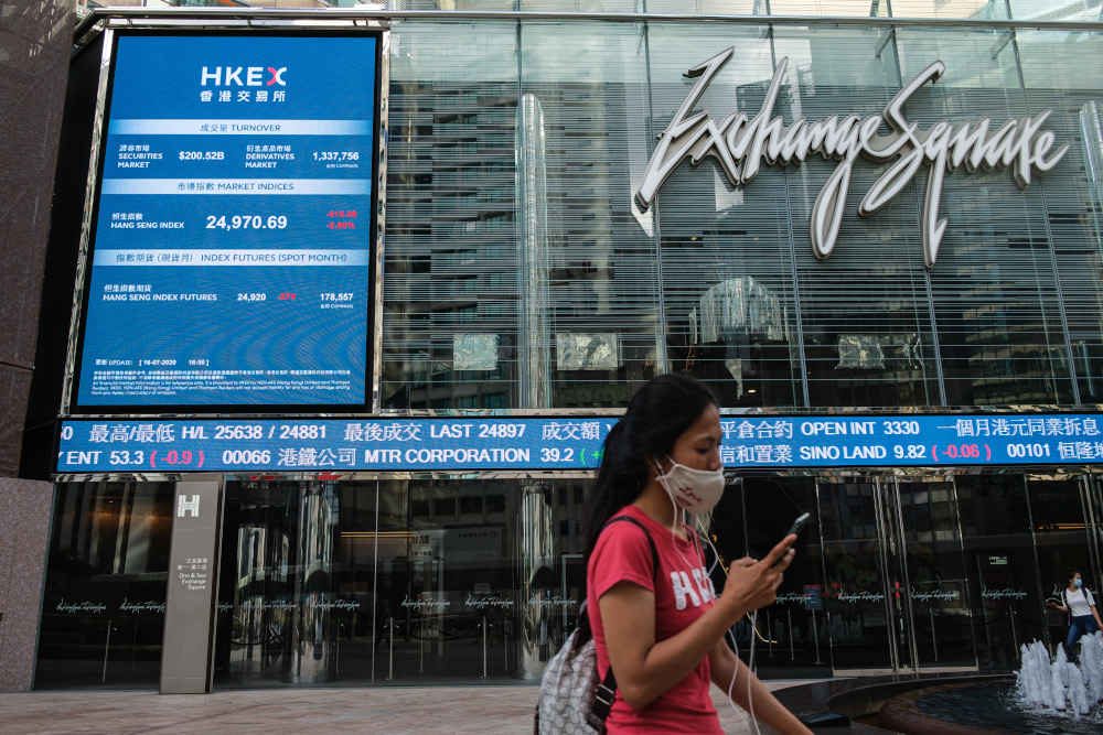 A woman wearing a face mask walks past a stocks display board outside Exchange Square in Hong Kong July 16, 2020, as the city experiences another spike in coronavirus cases. u00e2u20acu201d AFP pic  