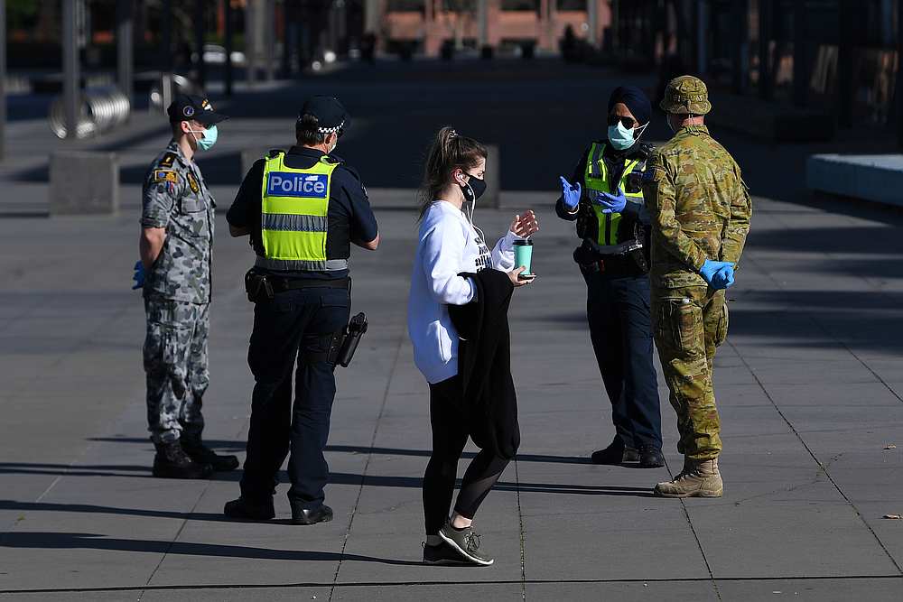 A person wearing a face mask walks past Victoria Police, Airforce and ADF personnel outside the Melbourne Museum with the city in Victoria, Australia under lockdown August 21, 2020. u00e2u20acu201d AAP Image via Reuters pic