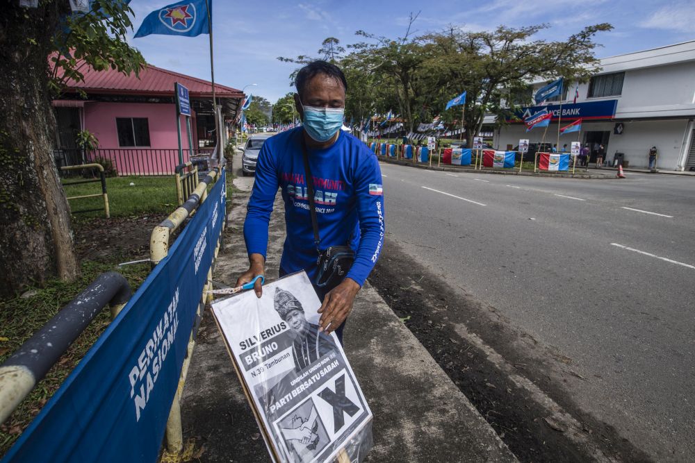 A worker is seen removing posters of PBS candidate Silverius Bruno after the party withdrew from the race to support STAR candidate Datuk Jeffrey Kitingan in Tambunan September 24, 2020. — Picture by Firdaus Latif