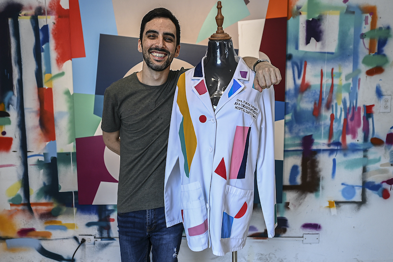 Panamanian artist Genaro Rodriguez poses with the white coat used by Dr Fulvia Vergara and decorated by him in Panama City. u00e2u20acu201d AFP pic