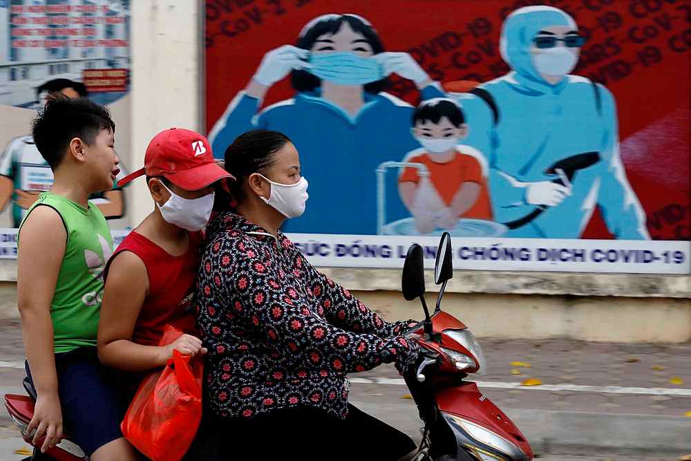 A woman wears a protective mask as she drives past a banner promoting prevention against Covid-19 in Hanoi, Vietnam July 31, 2020. u00e2u20acu201d Reuters pic