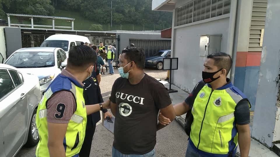 Accused Dinesh Kumar (centre) being escorted by policemen before he was charged with six counts of rape, sodomy, extortion and injuring a woman in Johor Baru today. u00e2u20acu201d Picture by Ben Tan