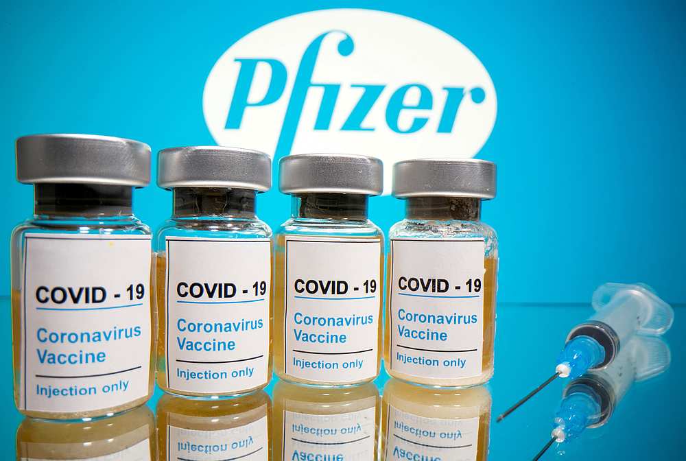 Vials with a sticker reading, 'Covid-19/Coronavirus vaccine/Injection only' and a medical syringe are seen in front of a displayed Pfizer logo in this illustration October 31, 2020. — Reuters pic