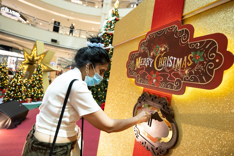 A shopper trying her luck at ‘Unlock A Christmas Surprise’ where RM5,000 worth of vouchers await. — Photo via Facebook/ Suria KLCC