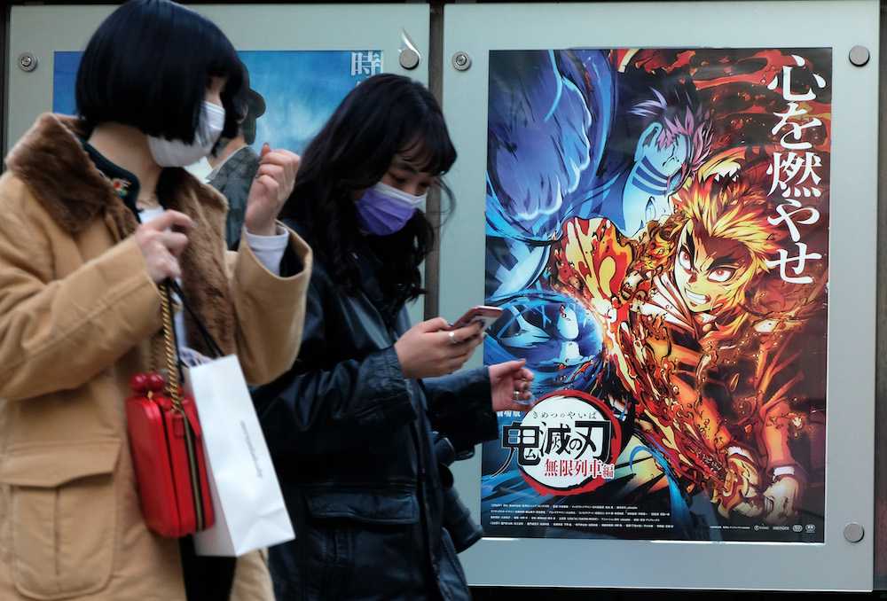Pedestrians walk past a poster promoting the anime movie Demon Slayer u00e2u20acu201d Kimetsu no Yaiba the Movie: Mugen Train u00e2u20acu201d at a cinema in Tokyo December 16, 2020. u00e2u20acu201d AFP pic