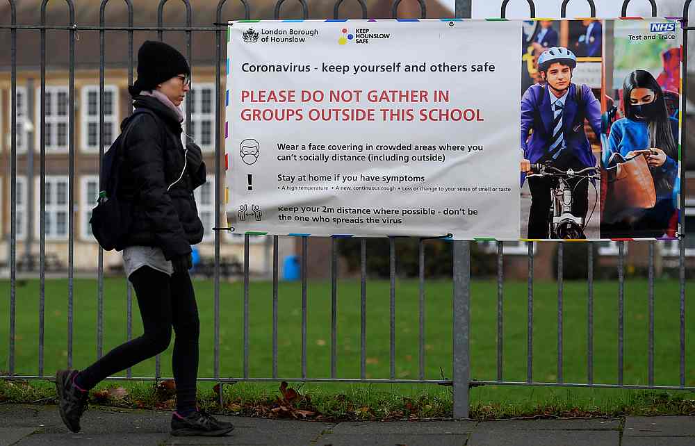 A woman walks past a social distancing health message outside of a secondary school in London, Britain December 29, 2020. u00e2u20acu201d Reuters pic