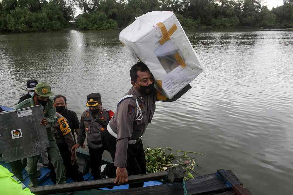 A police officer carries a ballot box from a boat to be distributed to a polling station ahead of the regional election in Sidoarjo, East Java province, Indonesia, December 8, 2020. u00e2u20acu201d Antara Foto via Reuters