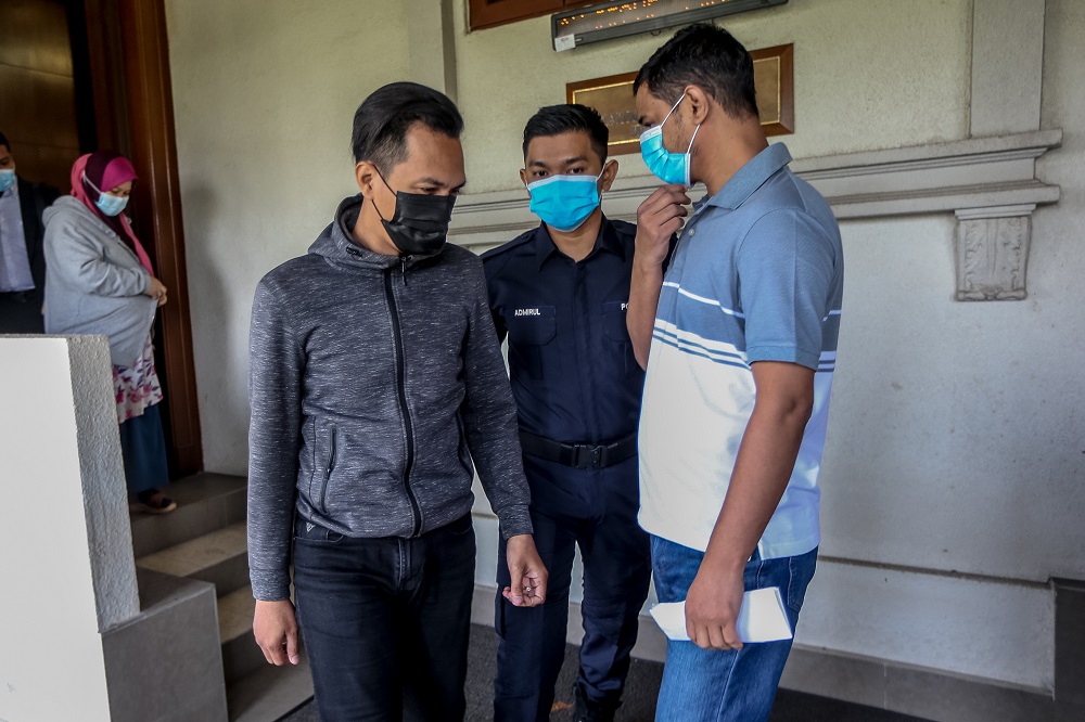 Immigration officer Mohd Al-Ridhuan Ahmad Zaini (left) is charged with receiving bribes totalling RM21,500 in exchange for helping foreigners who had committed immigration offences to leave Malaysia. u00e2u20acu2022 Picture by Firdaus Latif
