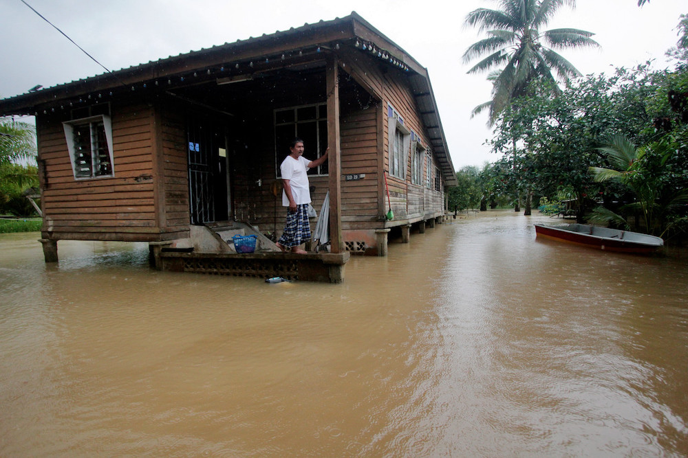 A resident of Kampung Gudang Rasau in Pahang looks on as flood waters surround his house. u00e2u20acu201d Bernama pic